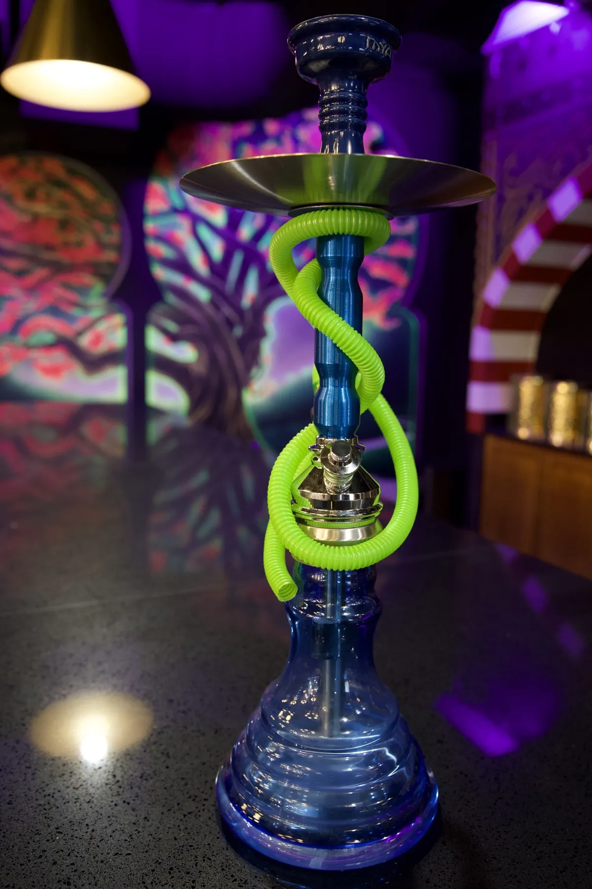 A hookah lit by green and purple neon